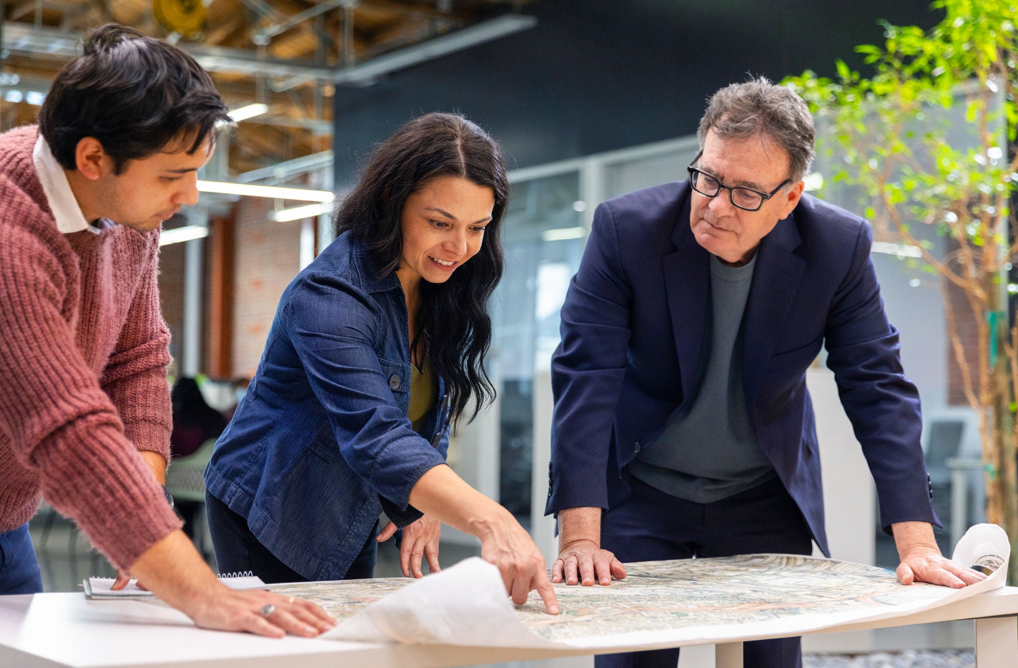 Three professionals look at a design and point out features