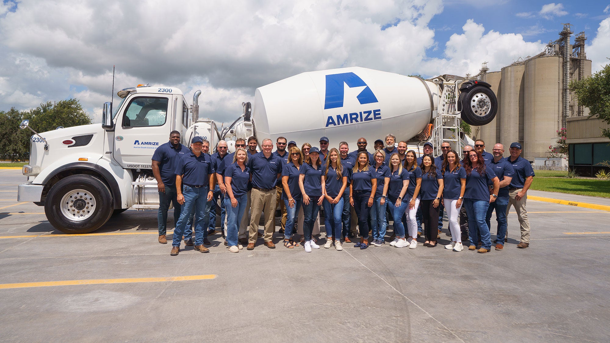 Amrize's Midlothian plant sets the backdrop of this photo featuring many Amrize collegues in front of an Amrize RMX truck for a group photo.