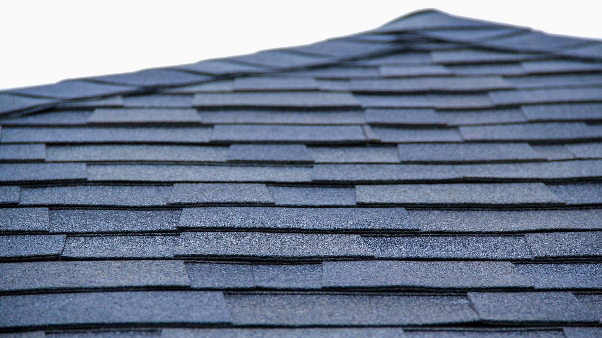 A close-up photo of a roof with overlapping shingles.