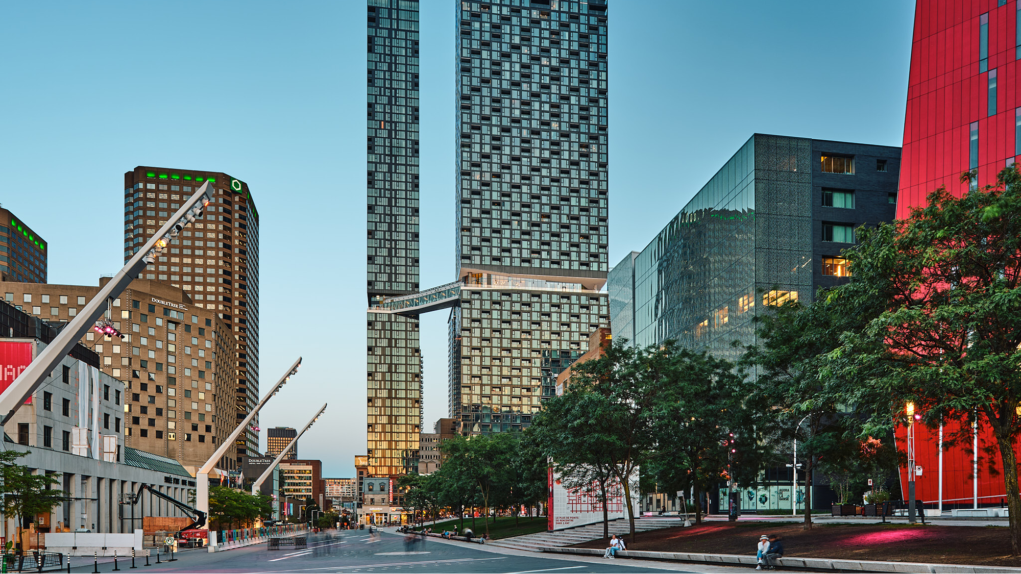 Cars driving over a long suspension bridge with mountains in the background