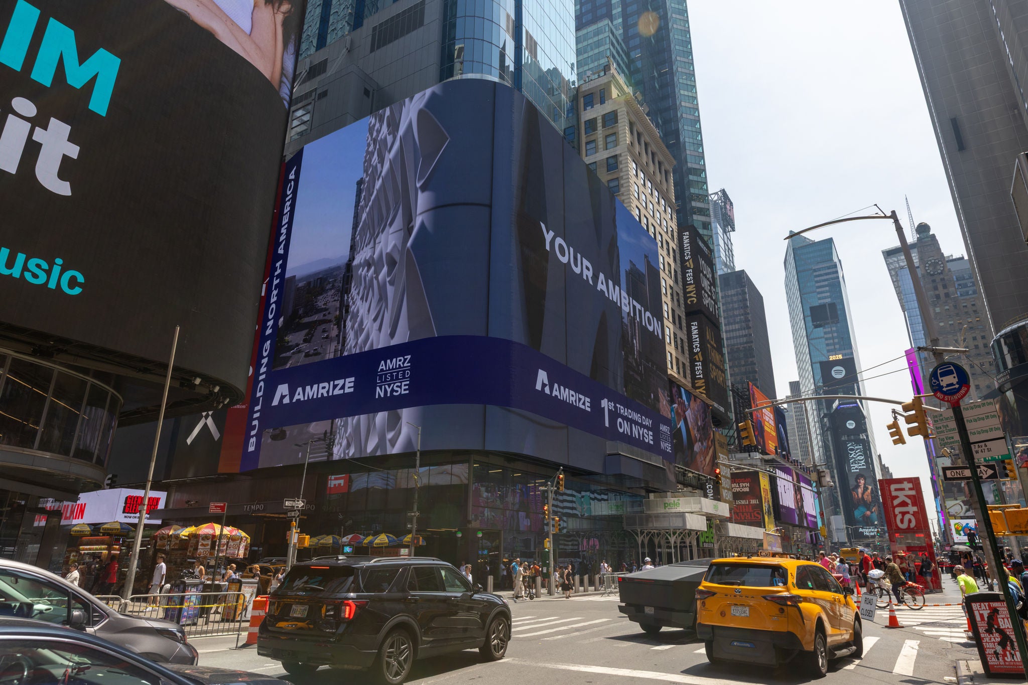 A billboard plays an ad as cars and taxis pass by
