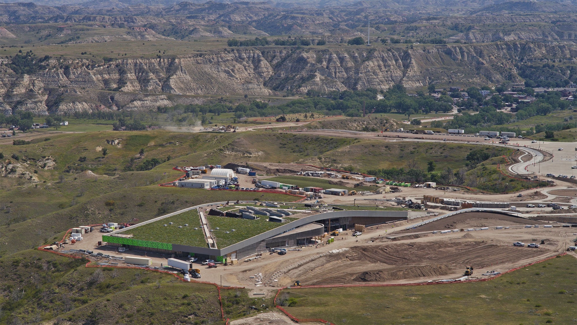 Aerial view of the Theodore Roosevelt Presidential Library construction site, highlighting the building's massive green roof integrated into the North Dakota Badlands landscape.