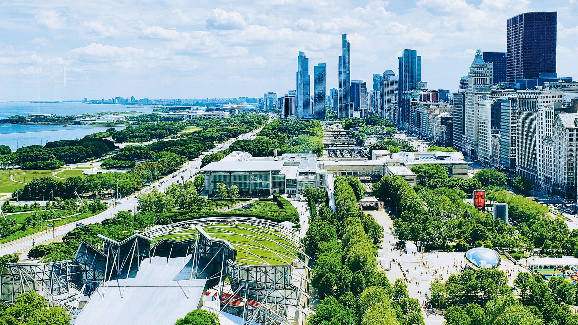 Parkland sits in front of a city skyline with high-rises on one side and water on the other.