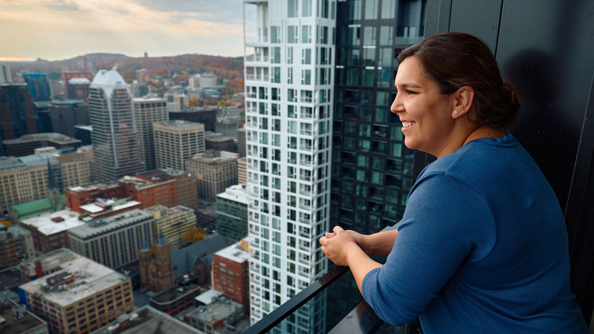 A women's profile portrait as she looks out on a balcony to the cityscape of Montreal, Canada.