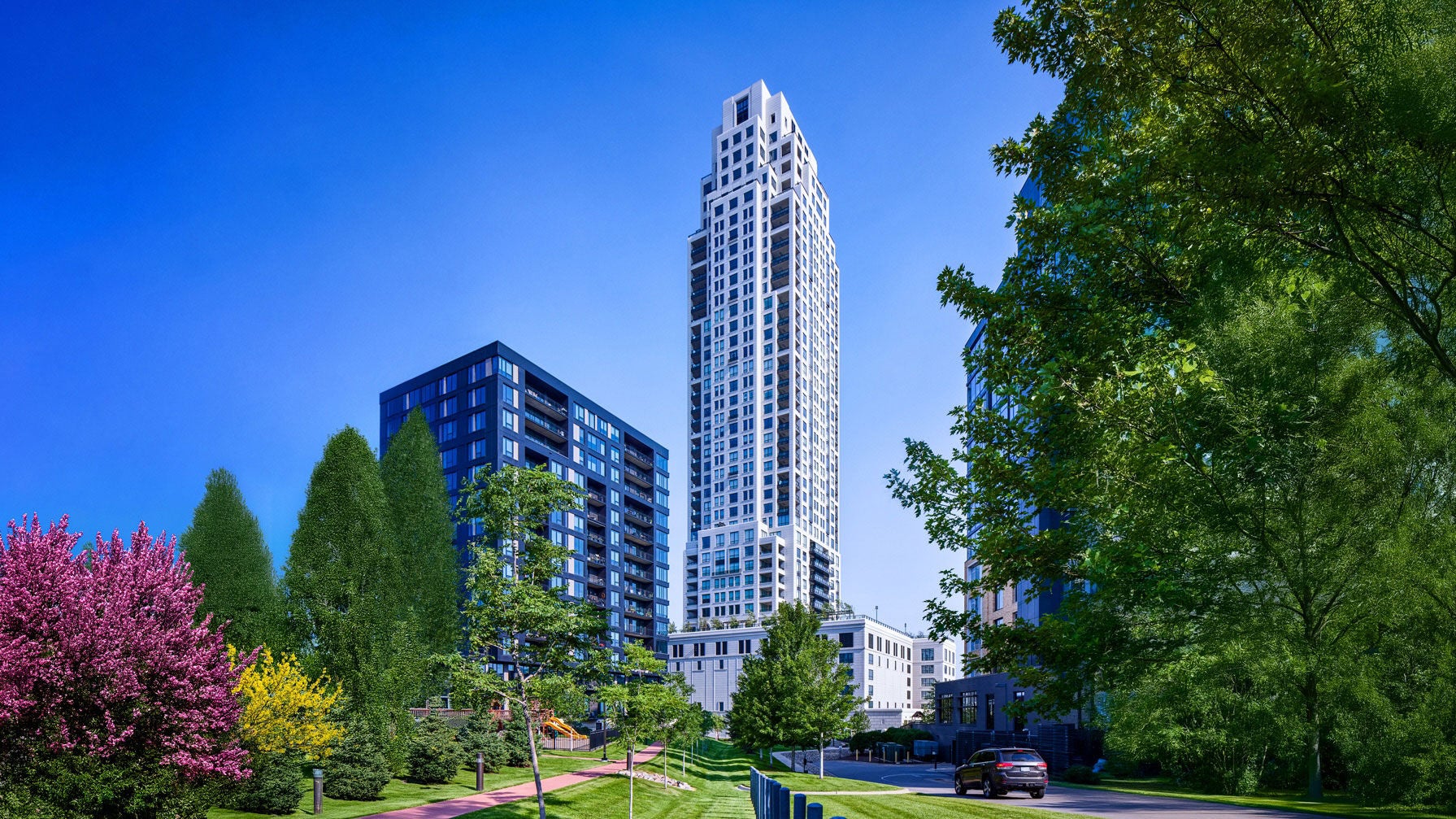 A concrete skyscraper rises into a clear blue sky behind a green park