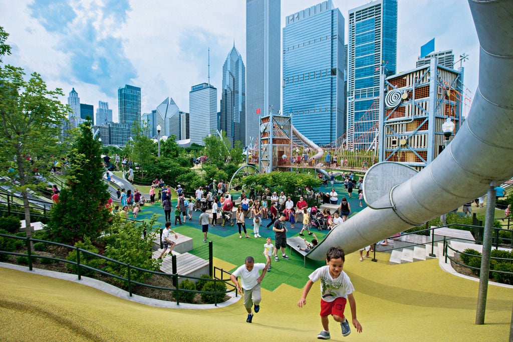 Kids run up a slope in a play area in a city park