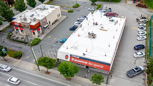 An aerial view of a commercial building with a new white roof