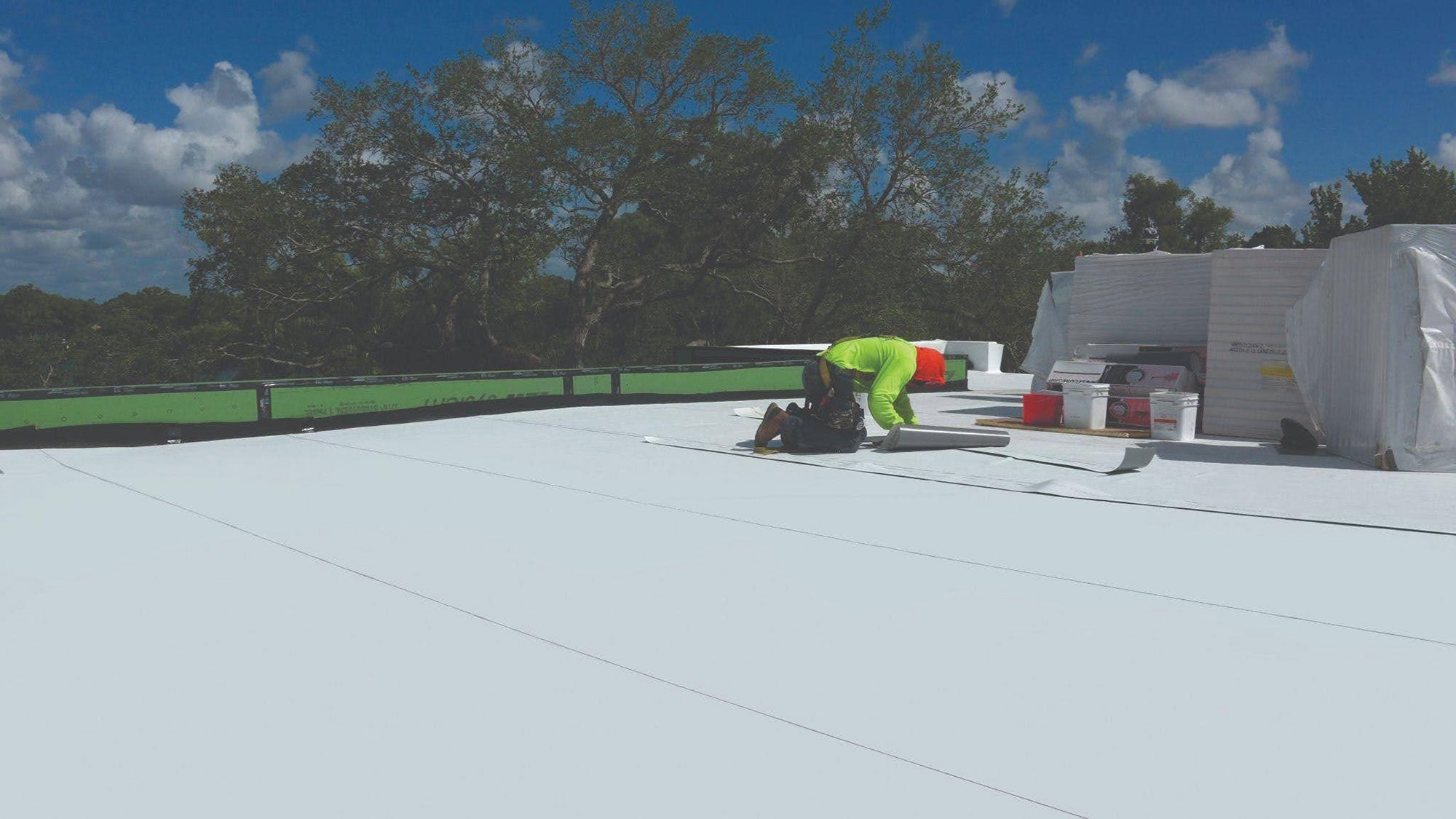 White Elevate UltraPly TPO membrane installed on a low-slope roof, reflecting sunlight as part of a complete Elevate roofing system including tapered ISOGARD polyiso insulation boards.