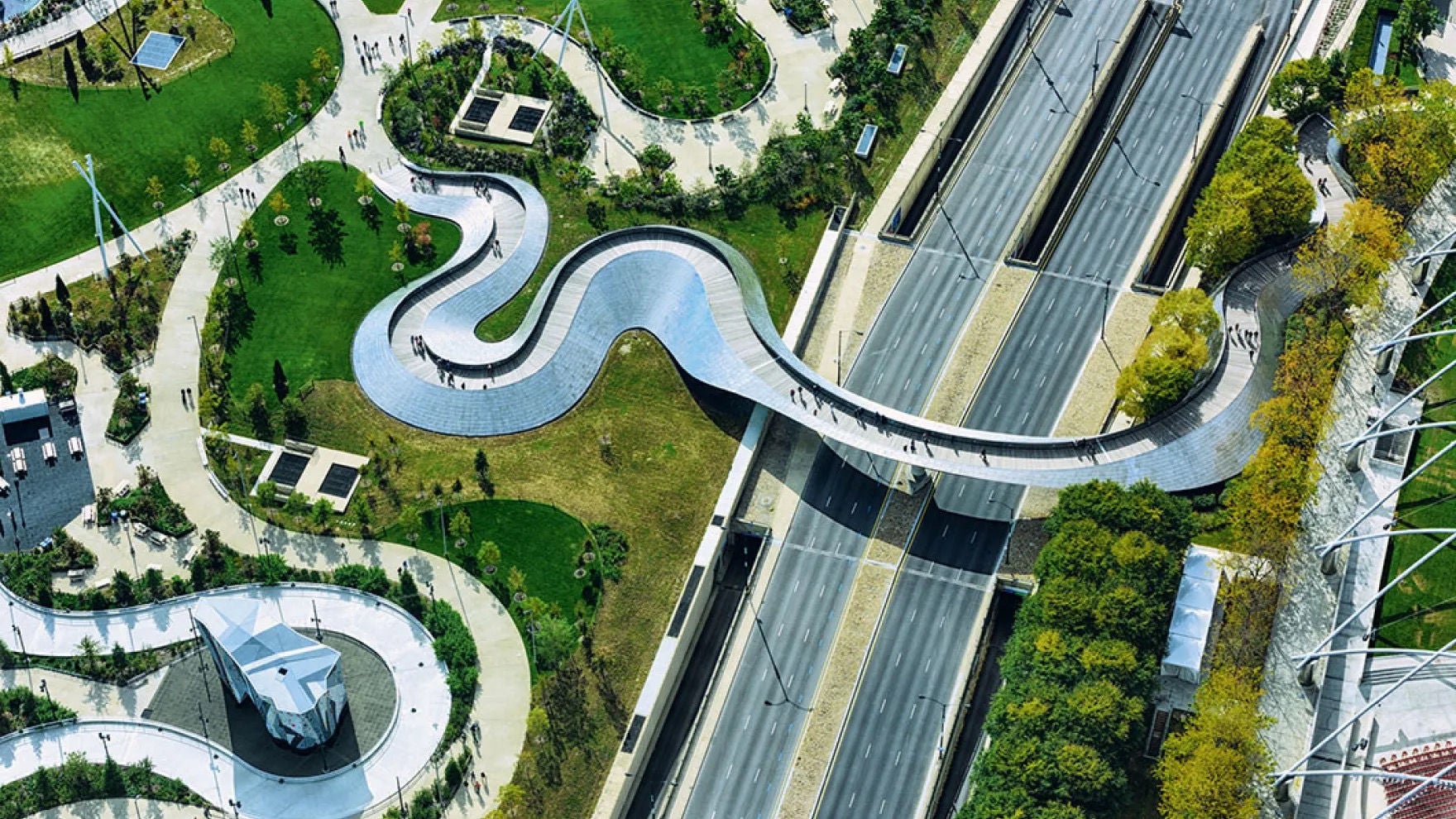 Aerial view of Maggie Daley Park in Chicago featuring a pedestrian bridge, pathways, and a road under a bridge