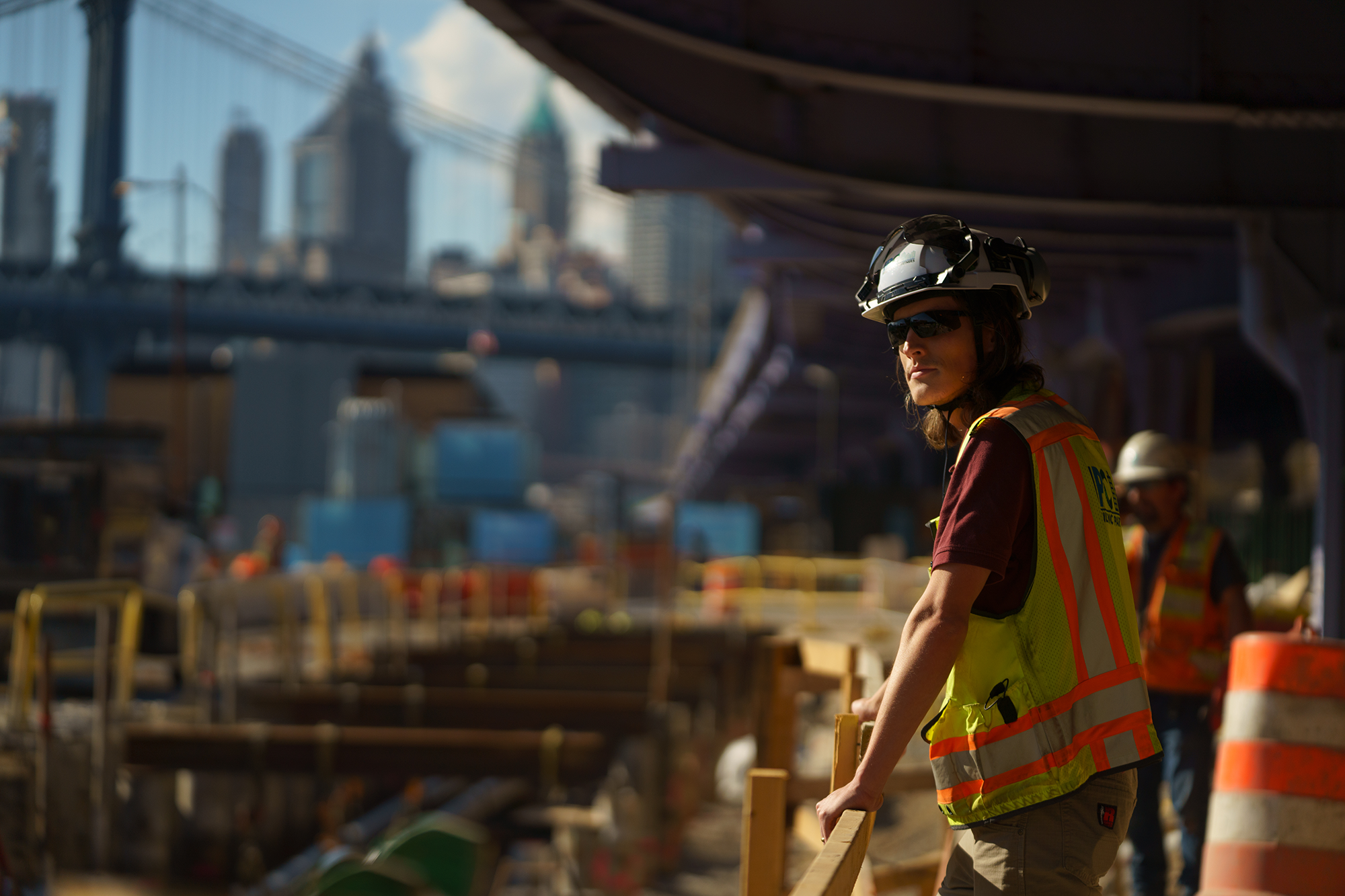 A man in personal protective equipment looking out at a large construction site