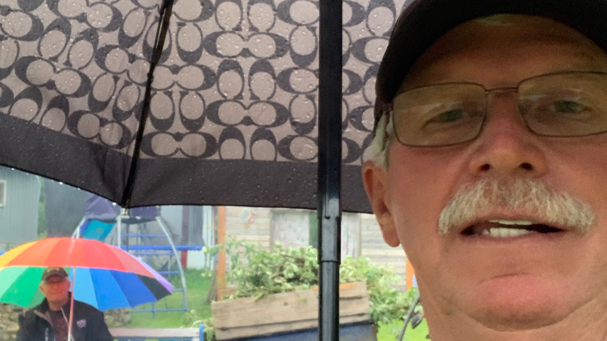 A man stands holding an umbrella and looks into the camera