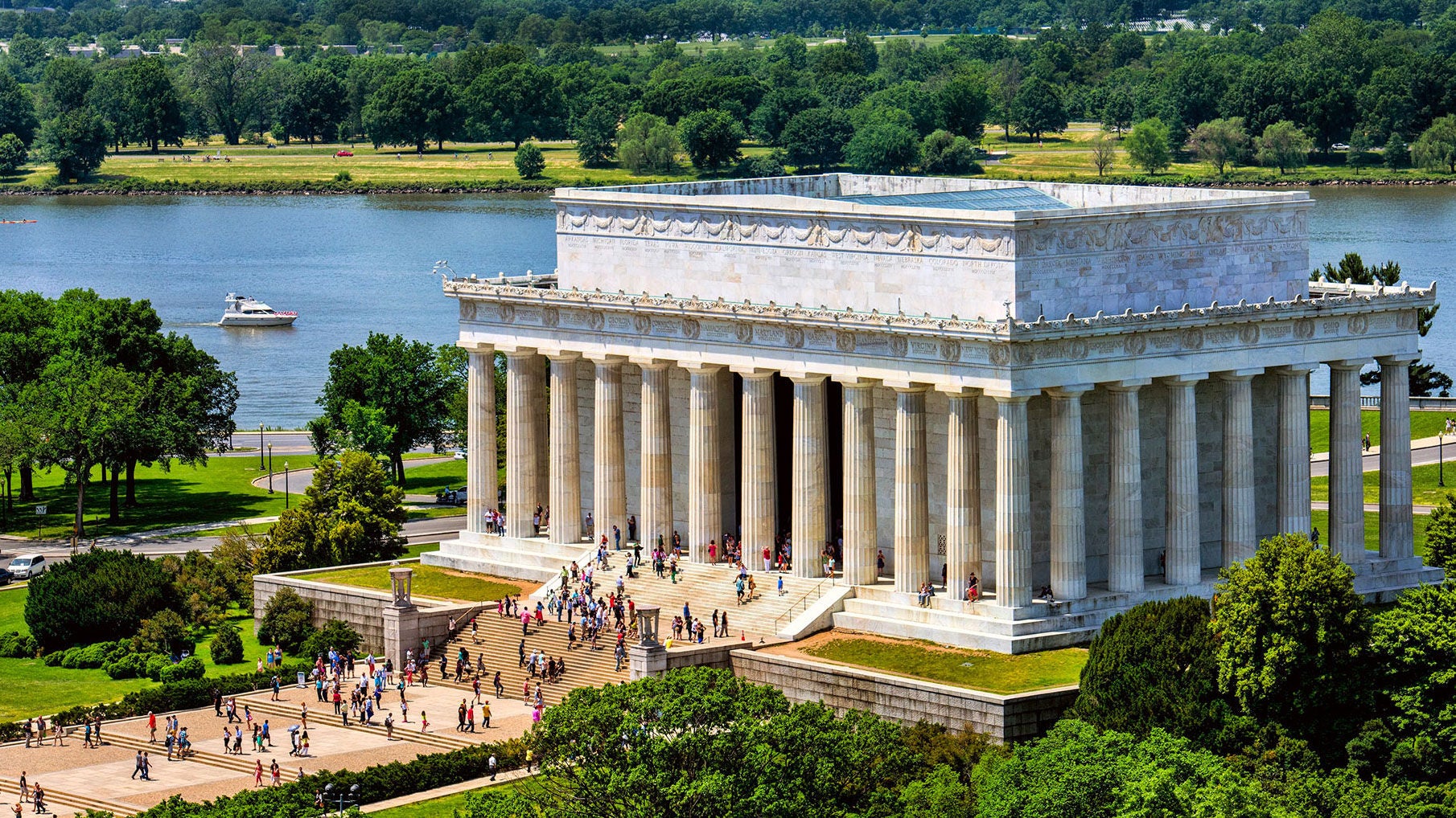 A large concrete monument with columns in front of a blue river