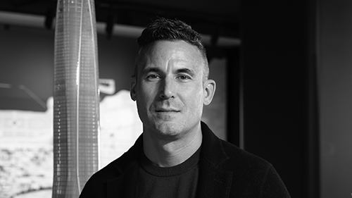 A black-and-white headshot of a man with short hair