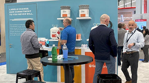 A group of people inspect a display of building envelope products at a trade show