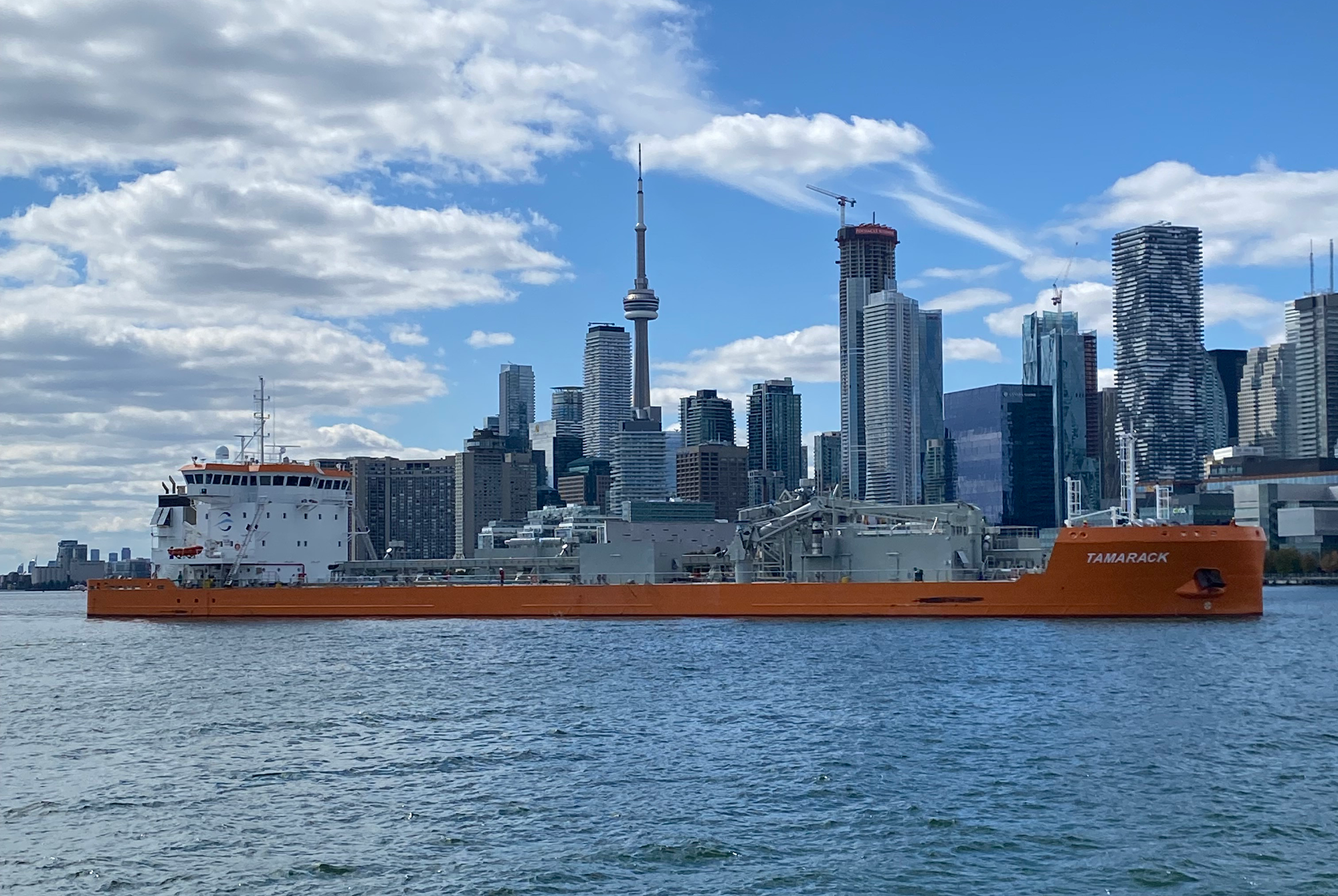 A large Great Lakes freighter sailing in front of the Toronto skyline