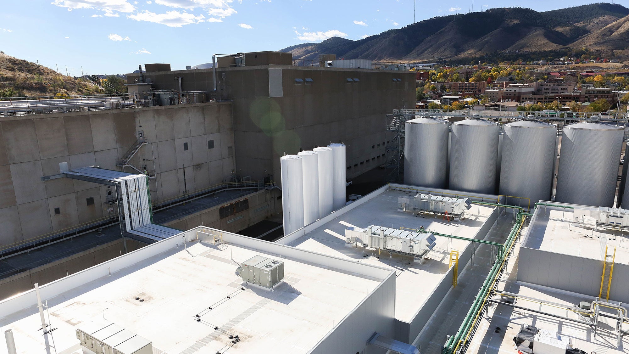 The roof of a large brewery with mountains set behind it.