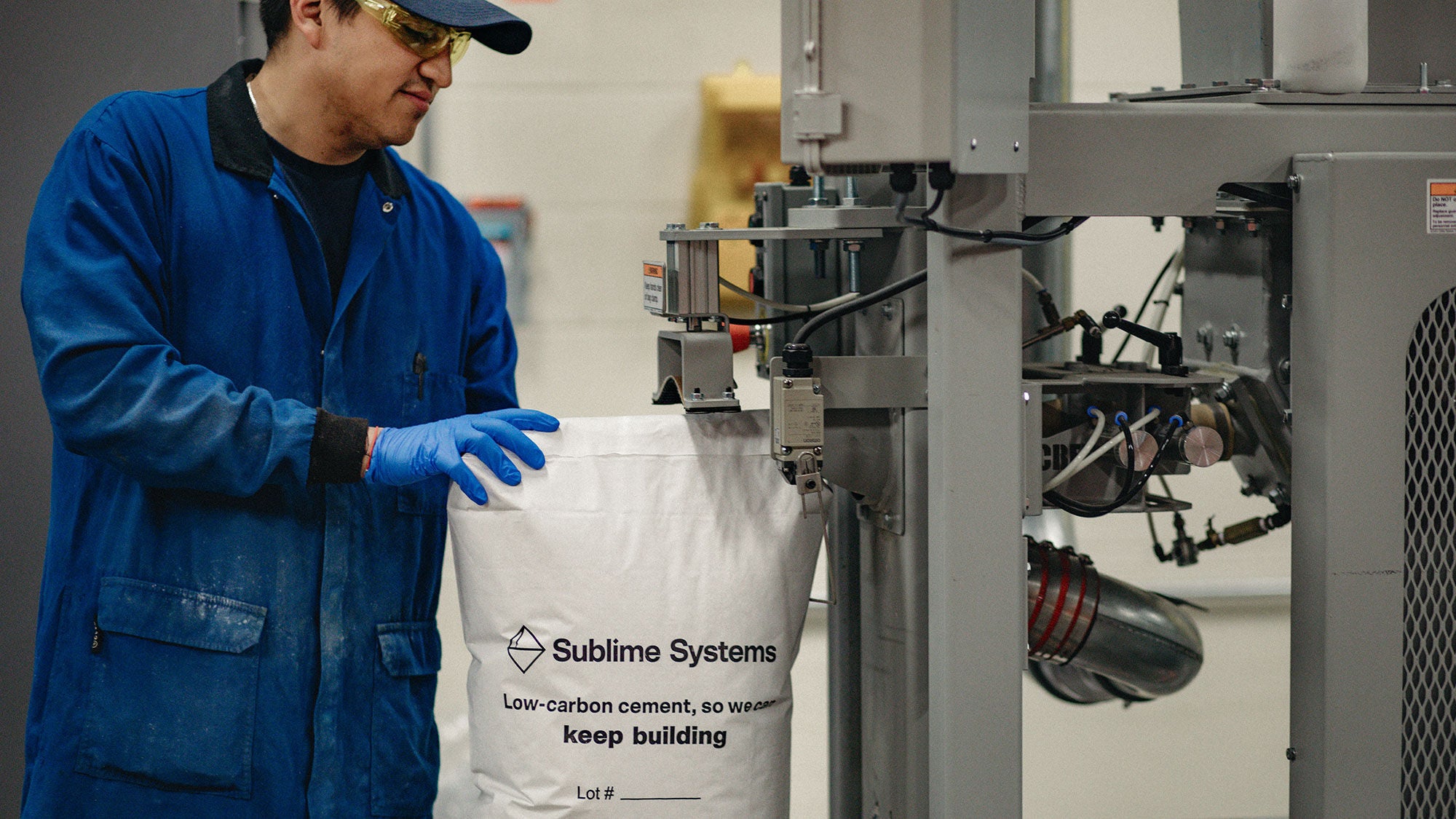 A man in blue coveralls bagging concrete at a machine