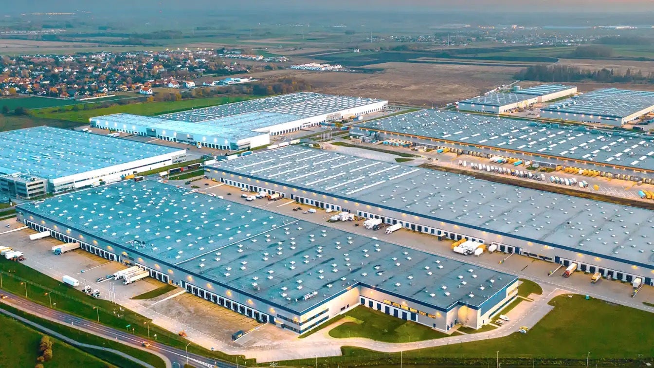 A group of large industrial buildings with semitrucks docked at some of the loading bays