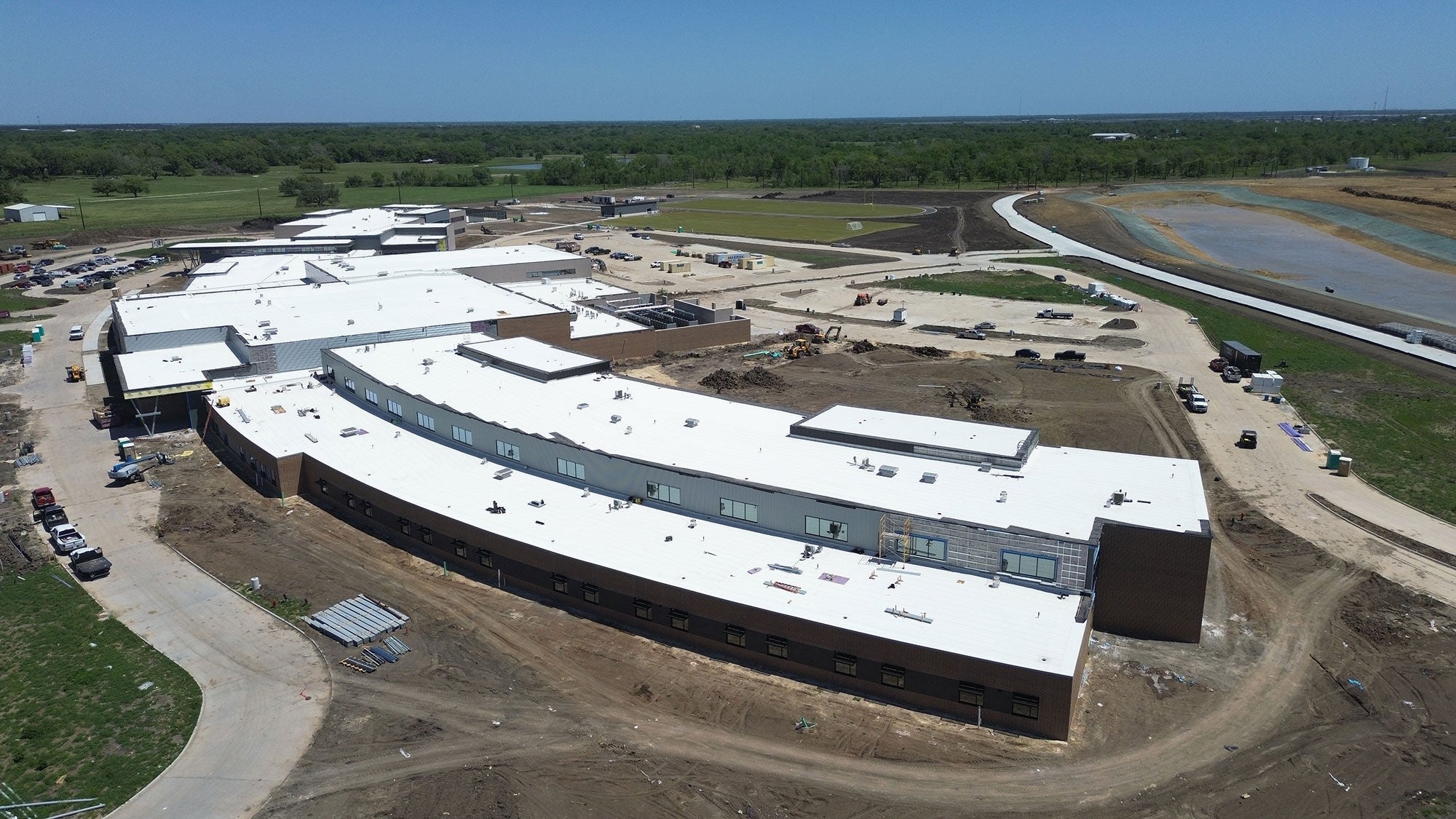 Large school building viewed from above, focused on the white roof which covers the entire surface area.