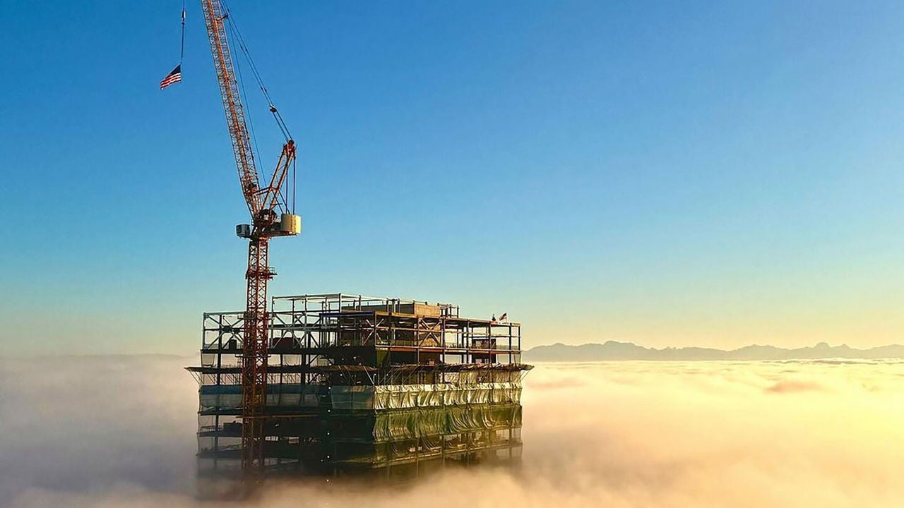 The top of a high-rise building under construction rising above the clouds.