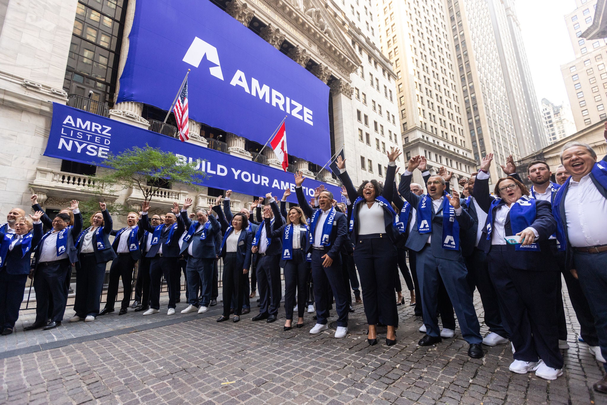 A group of employees stand and cheer in front of the New York Stock Exchange
