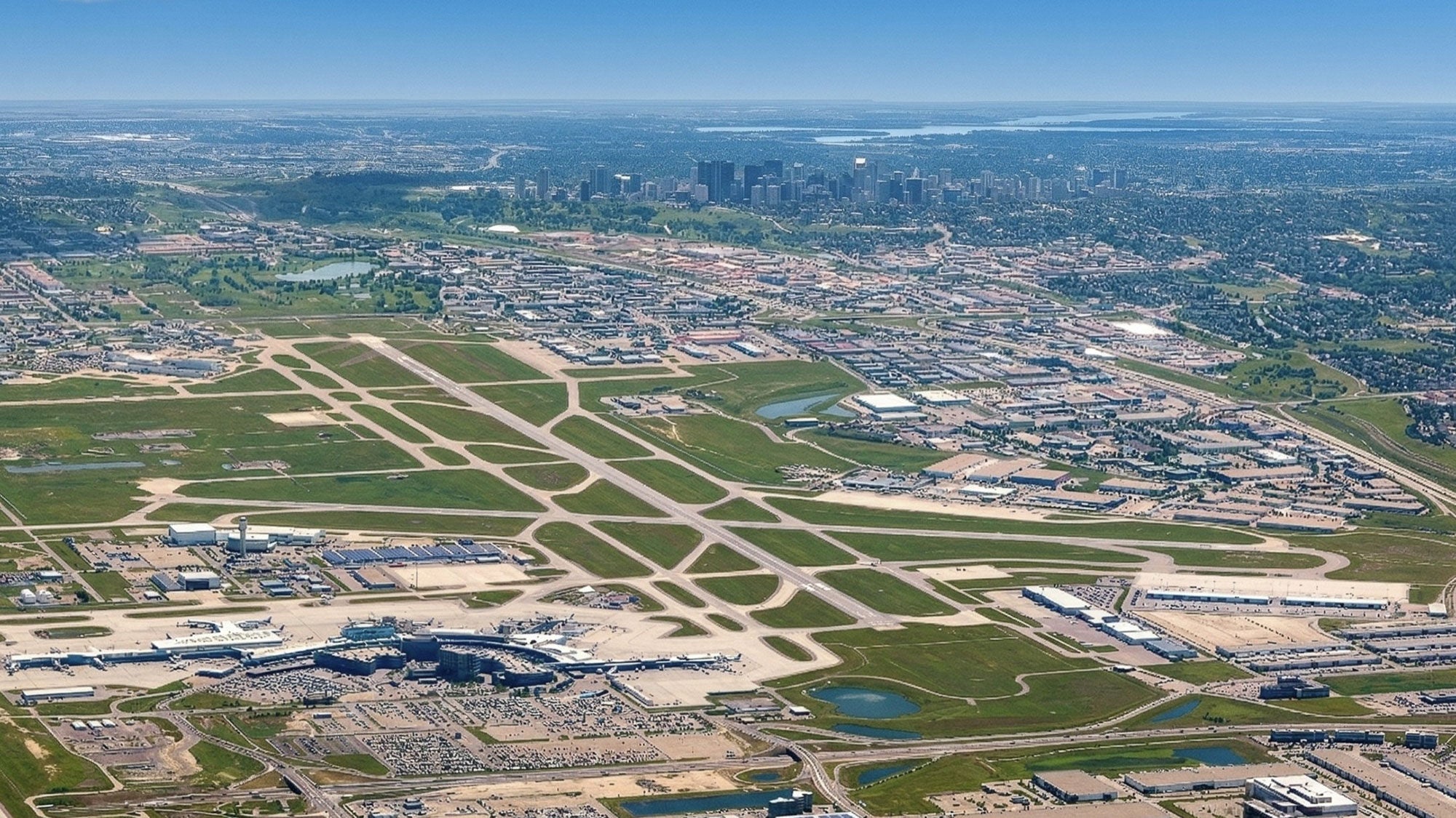 Aerial shot of YYC Calgary International Airport with the downtown city skyline visible in the distance.