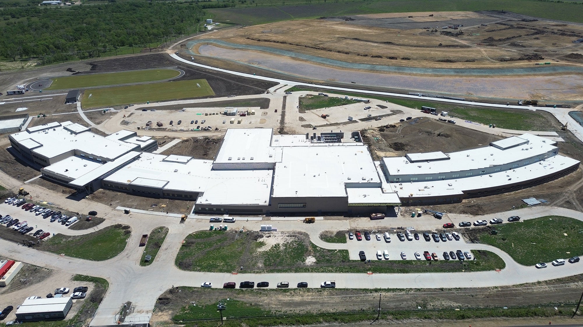 Large school building viewed from above, focused on the white roof which covers the entire surface area.