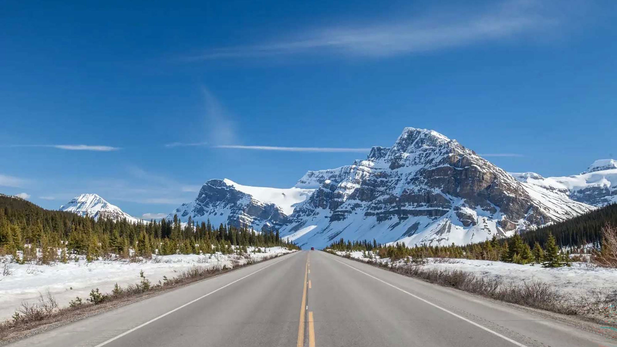 A clean road stretching towards a snow-covered mountain in the distance