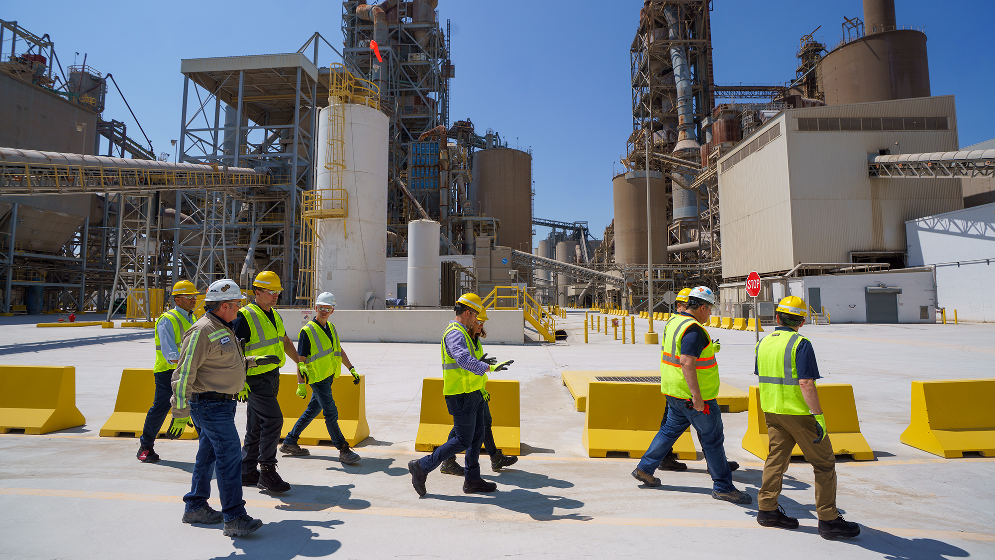 A group of workers in personal protective equipment walking through a factory
