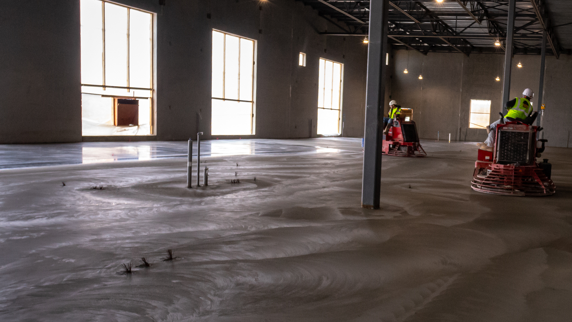 Workers drive machines to finish concrete