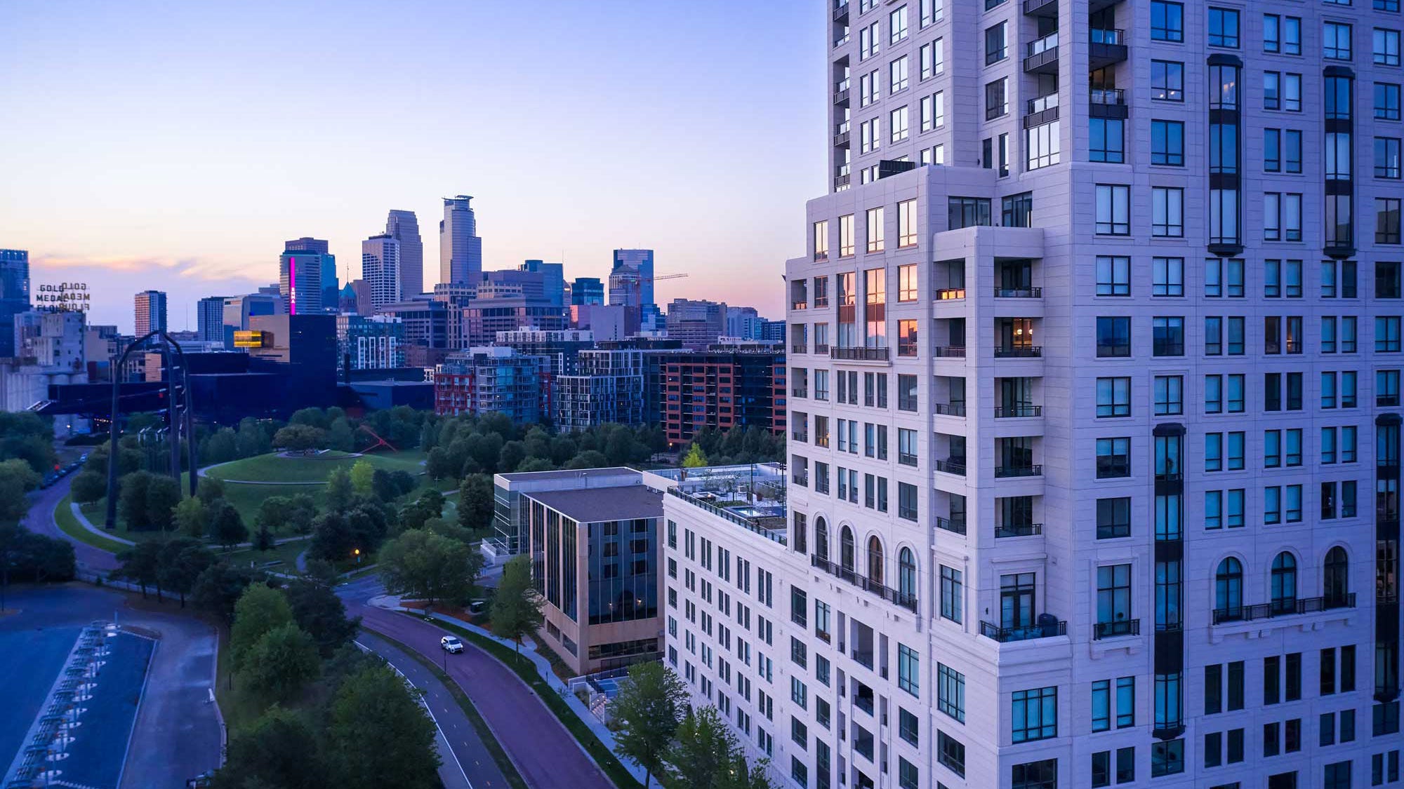 A large concrete skyscraper seen up close with a cityscape behind it