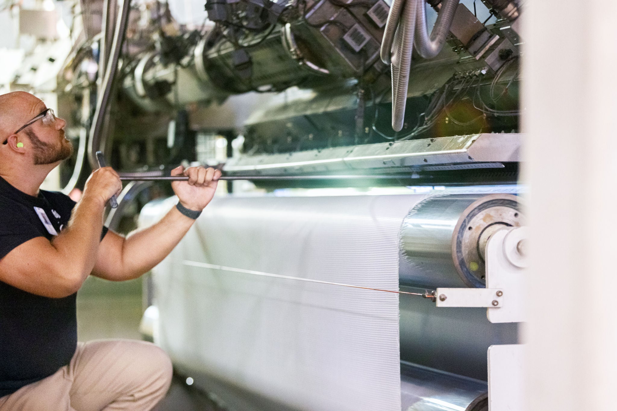 A worker in safety glasses operates a machine