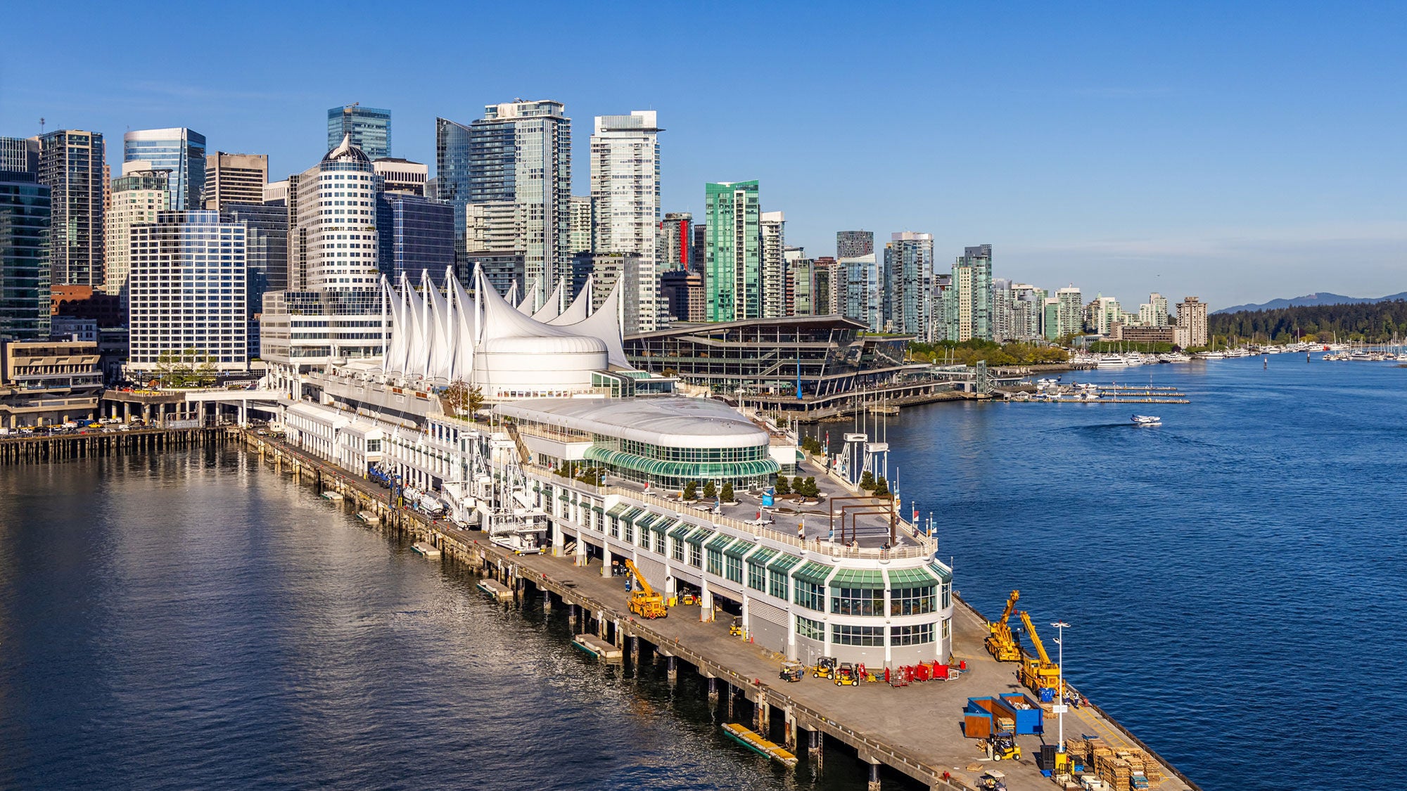 Vue d’une ville depuis l’eau. Des gratte-ciels densément regroupés bordent l’eau. 
