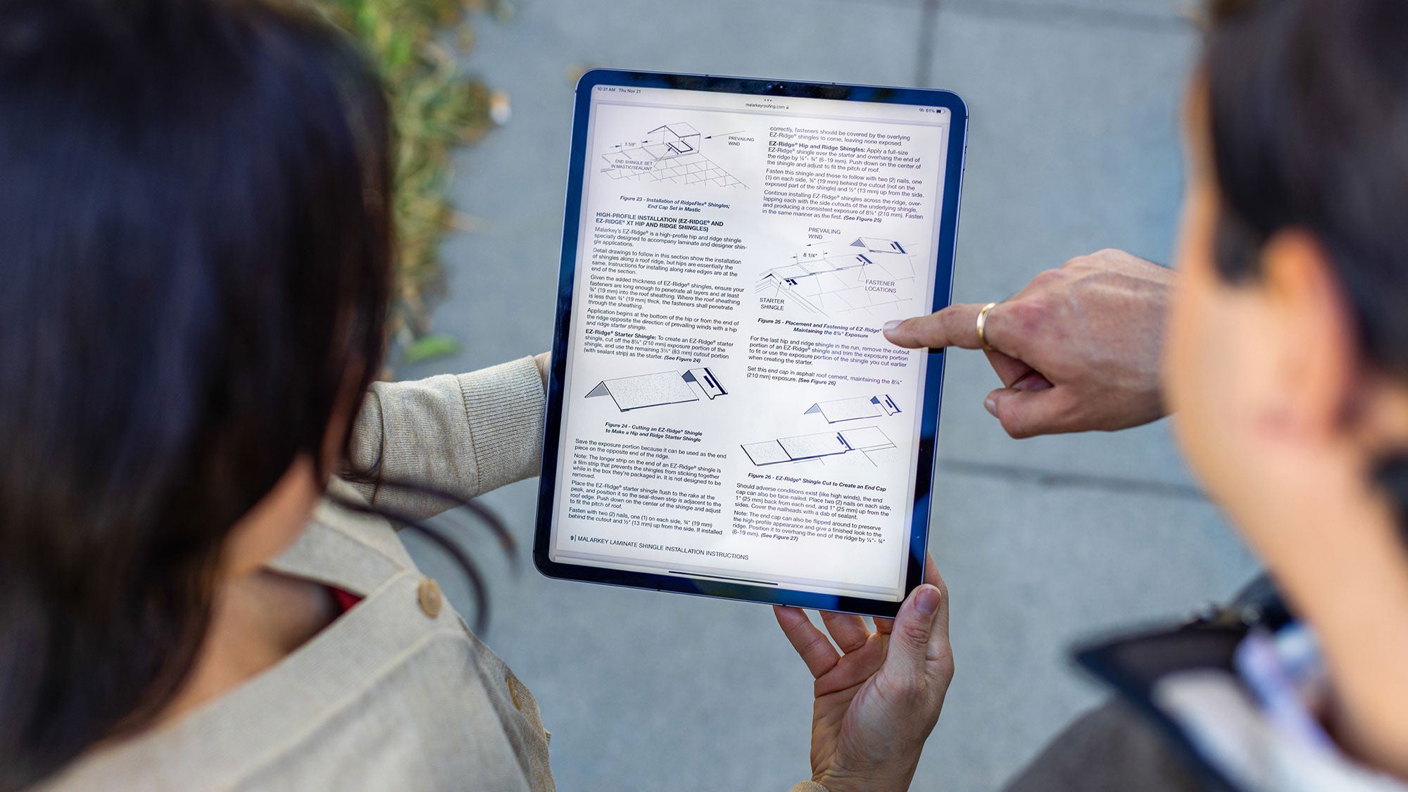 Two people gaze and point at a tablet screen