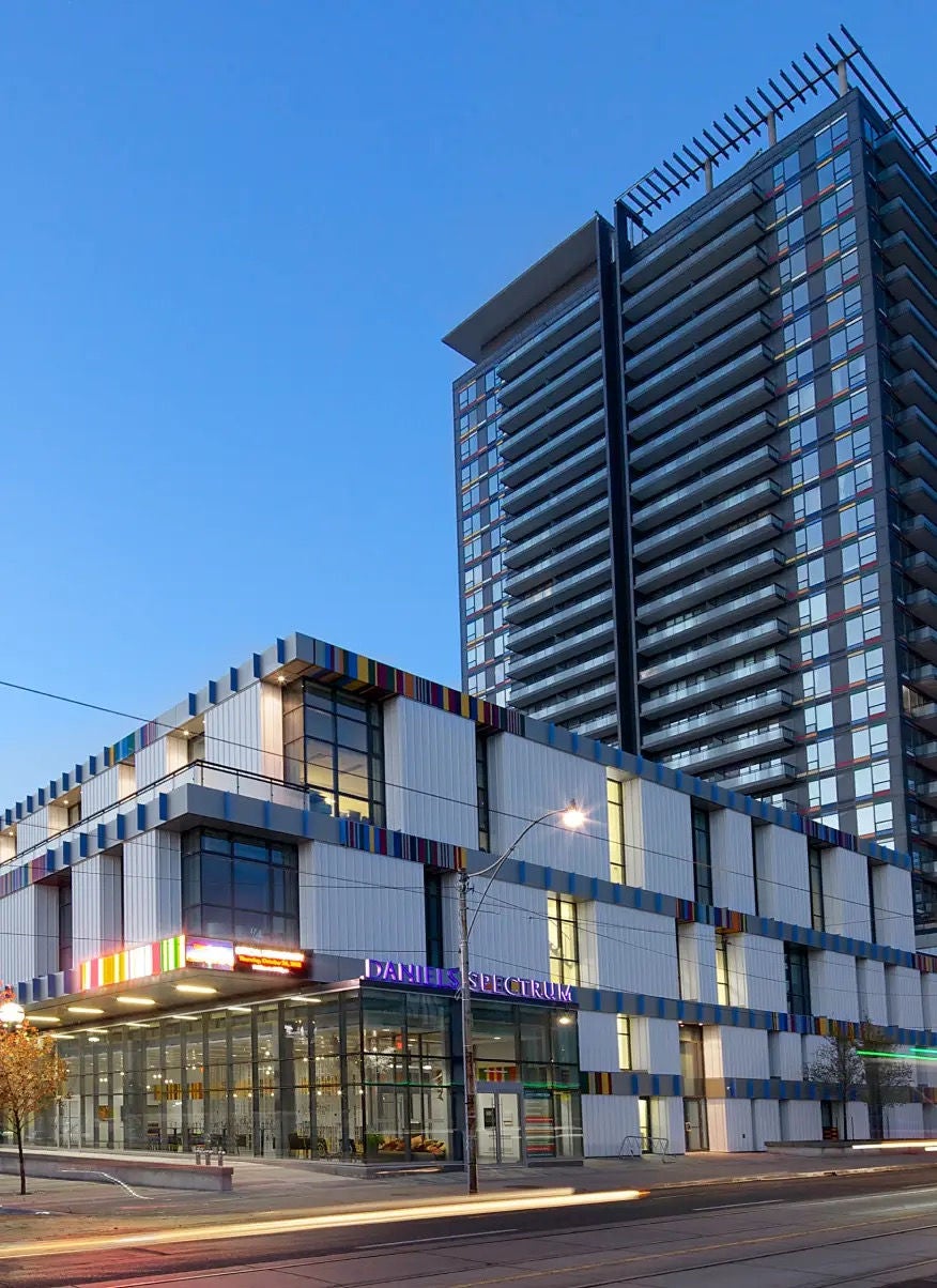 A modern glass tower rising from the street at sunset