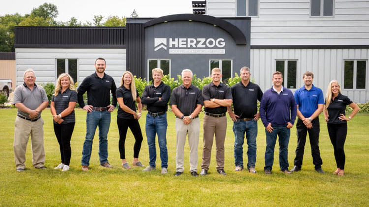 A group photo of a team wearing Herzog Roofing branded shirts