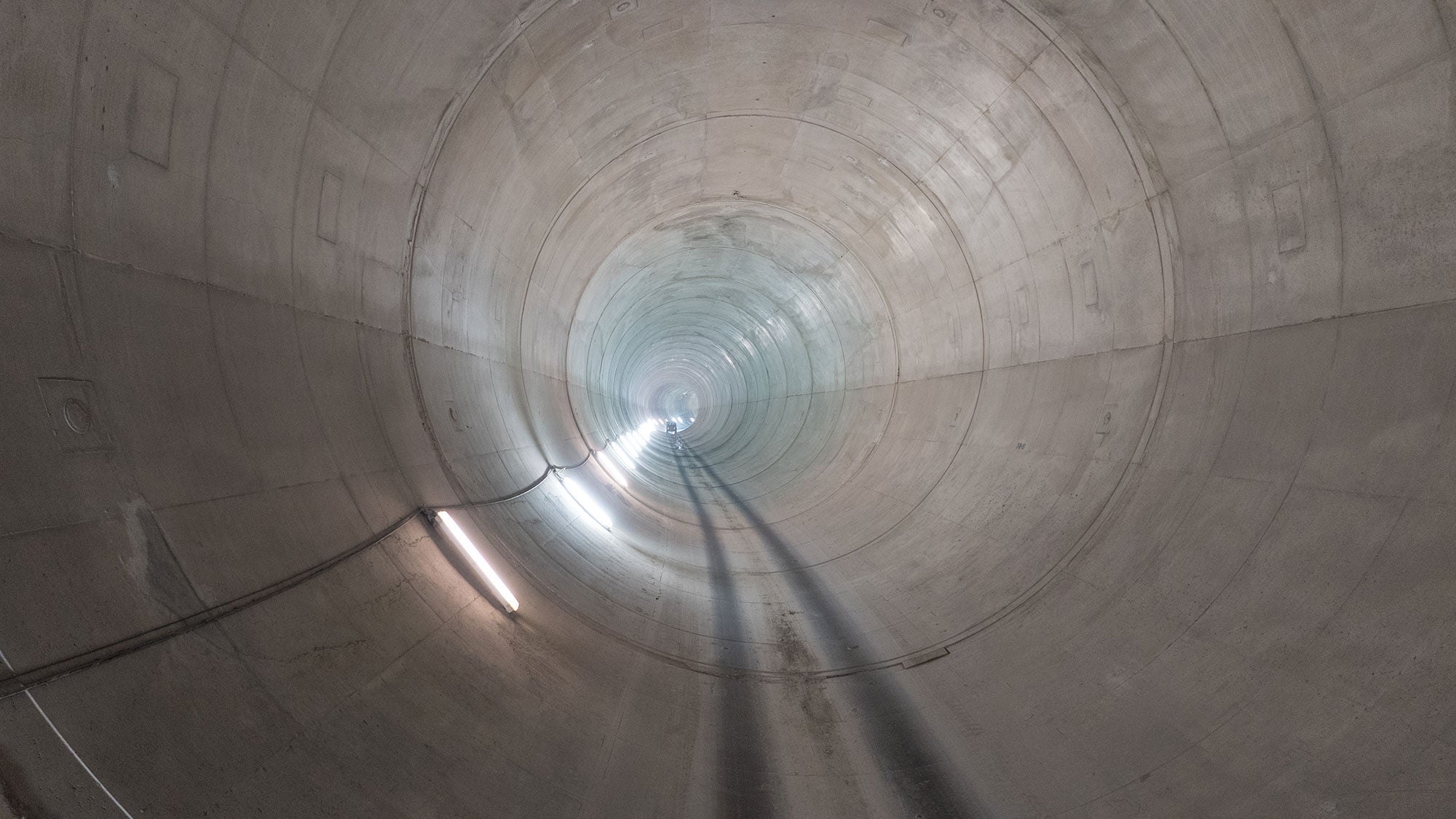 Circular underground concrete drainage tunnel looking down the length.