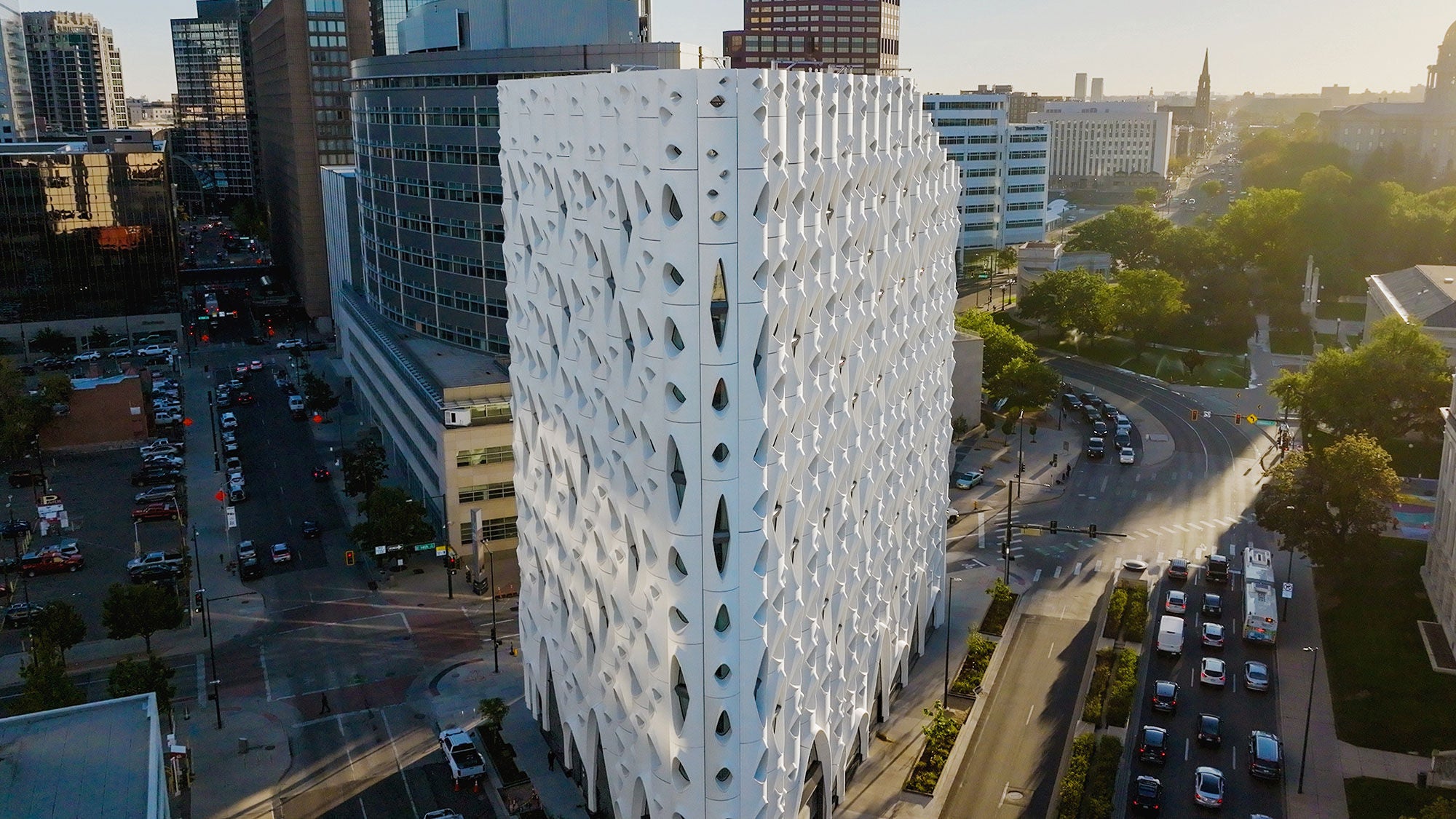 A large concrete hotel tower on a street corner with ovalic windows at each floor