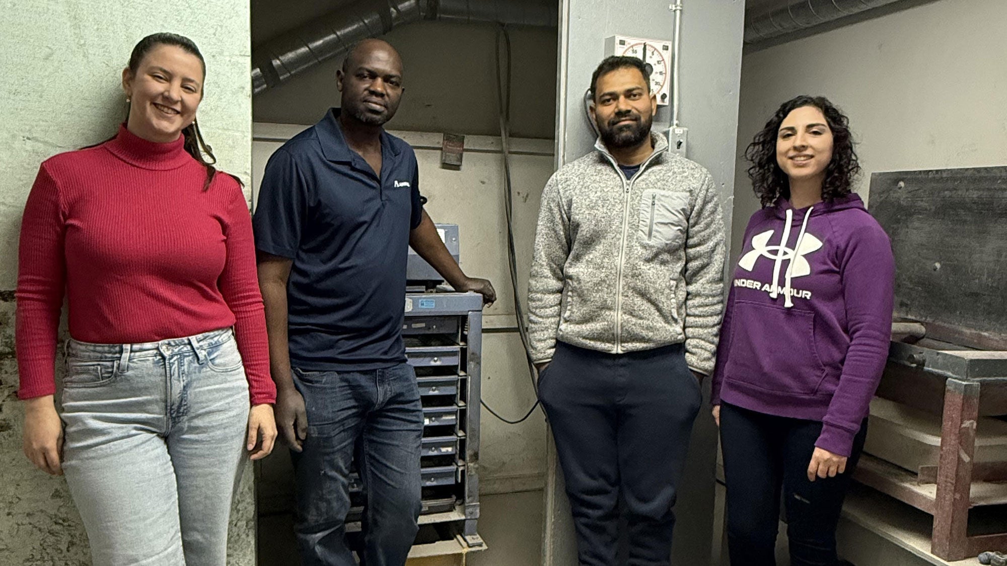 Amrize quality control team, including Abdul Muzungu, posing in one of Amrize’s quality control labs with materials testing machinery.