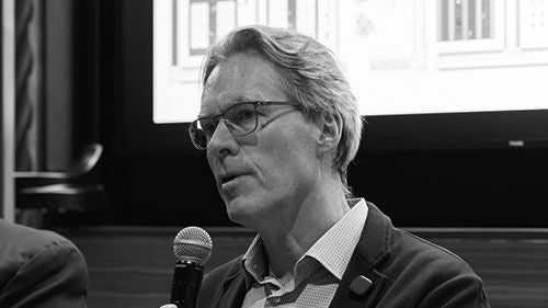 A black-and-white headshot of a man with glasses