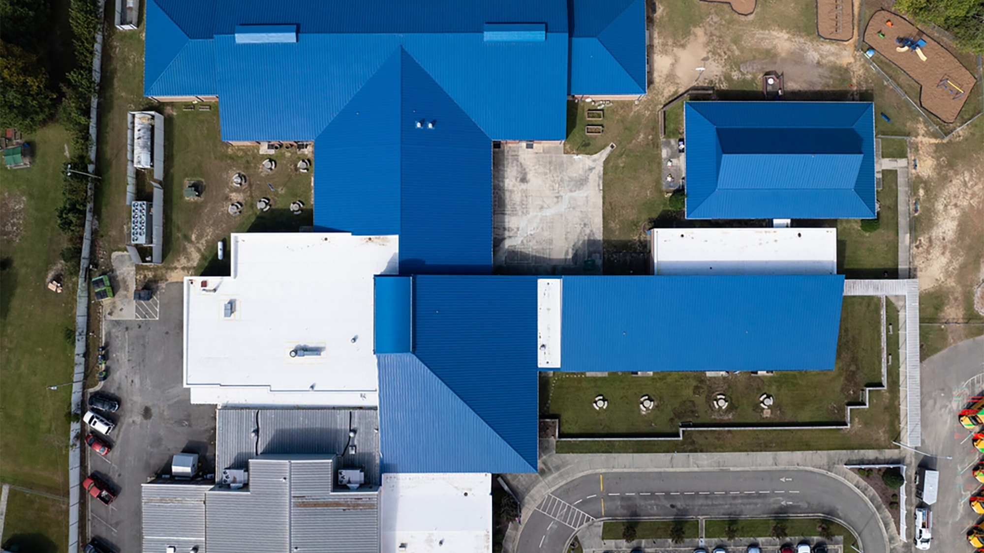 A blue metal roof on an elementary school, seen from above.