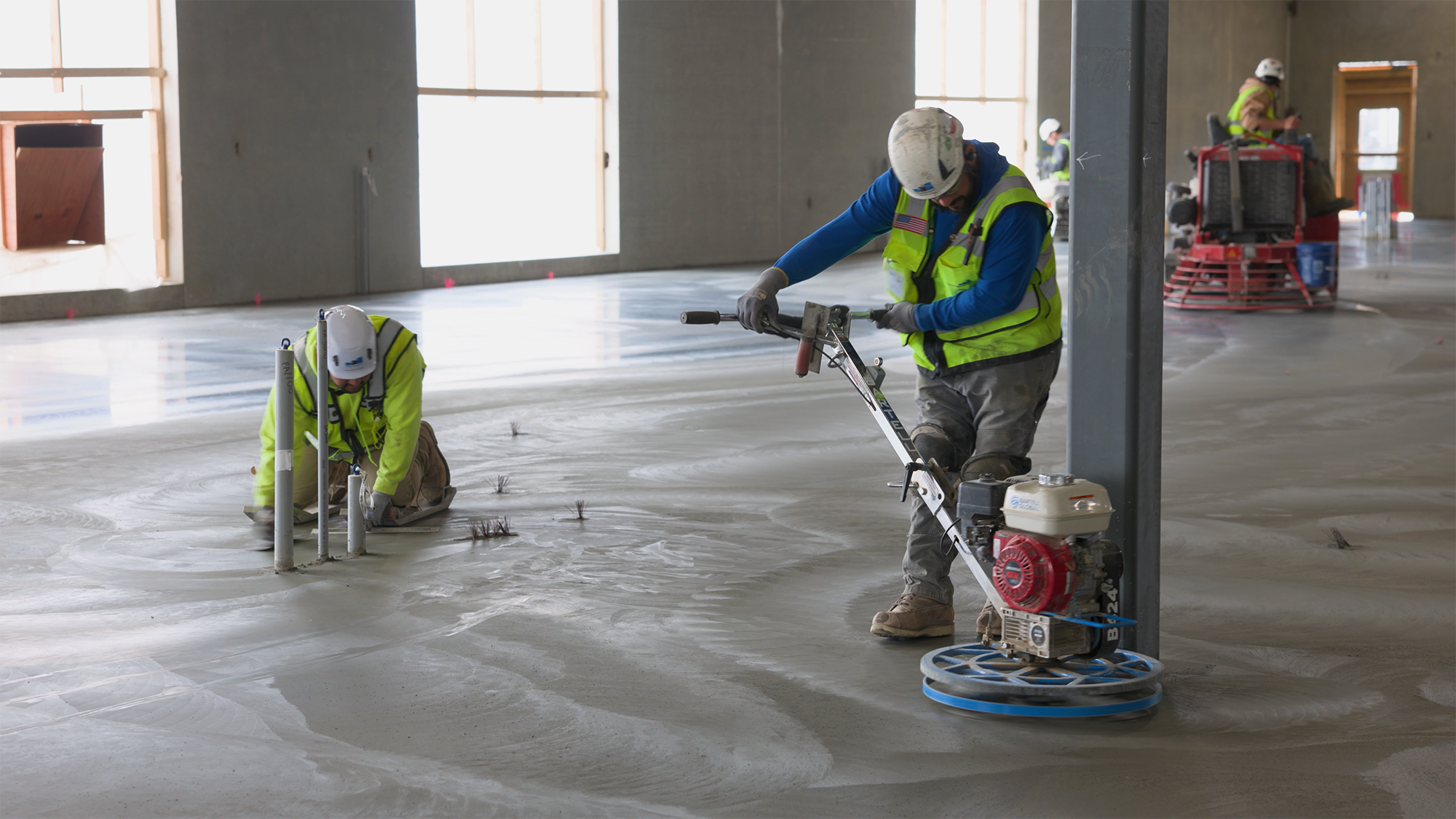 Construction workers use machines and tools to smooth concrete