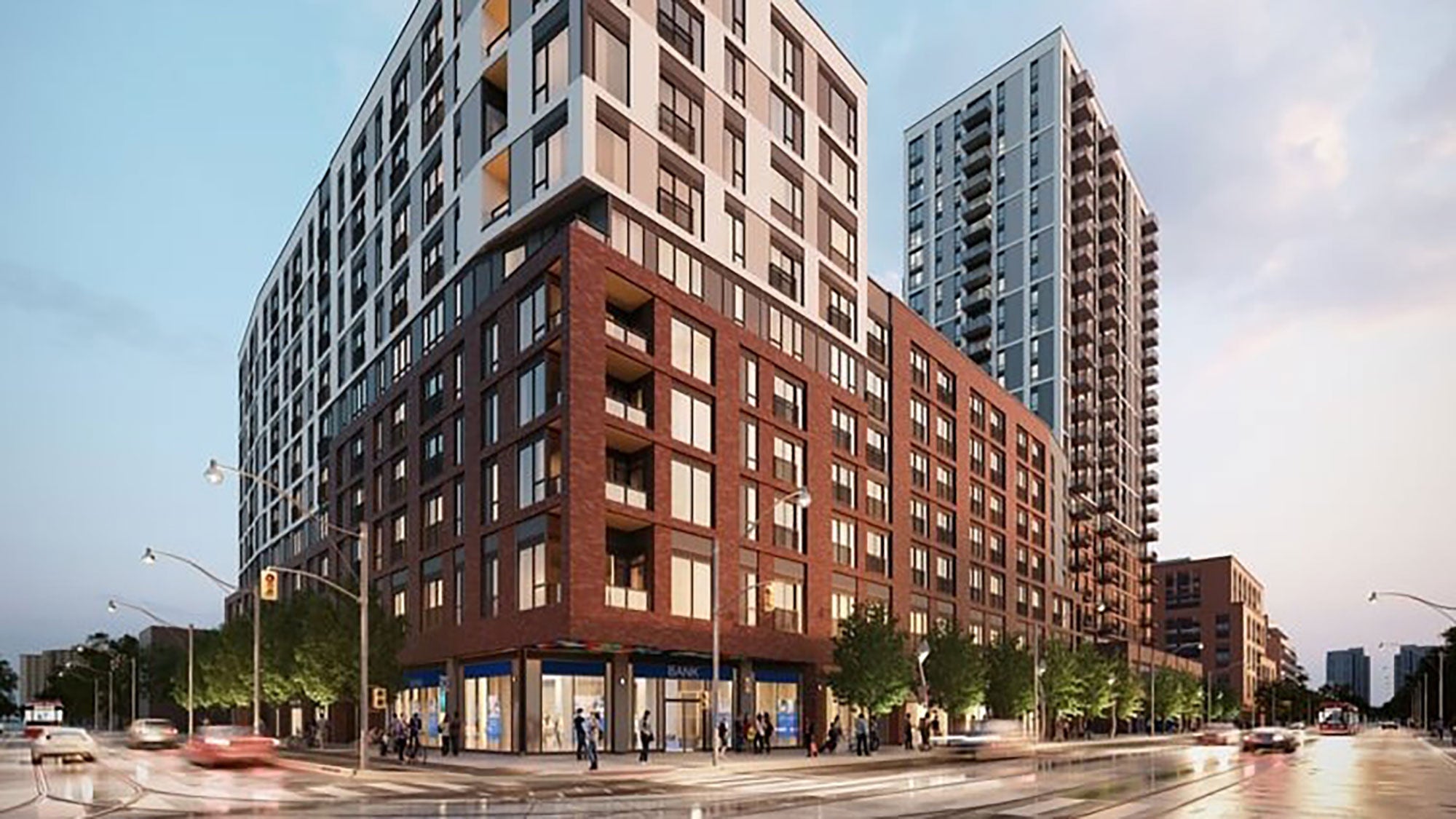 Daniels on Parliament building at dusk, featuring a multi-story apartment building with a brick and glass facade. Streetlights illuminate the bustling intersection below.