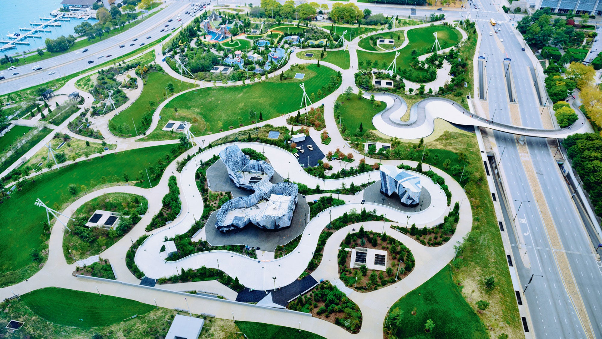 An aerial shot of a city park sandwiched between two major roads and a body of water.