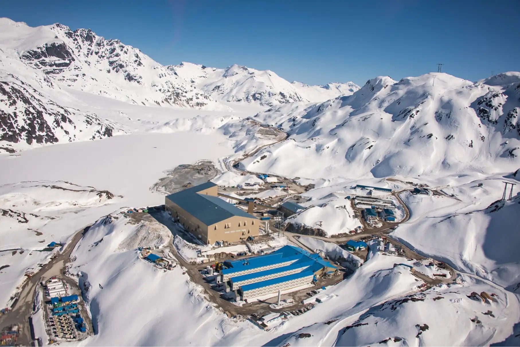 A large mining facility and other structures located in a snowy mountain environment.