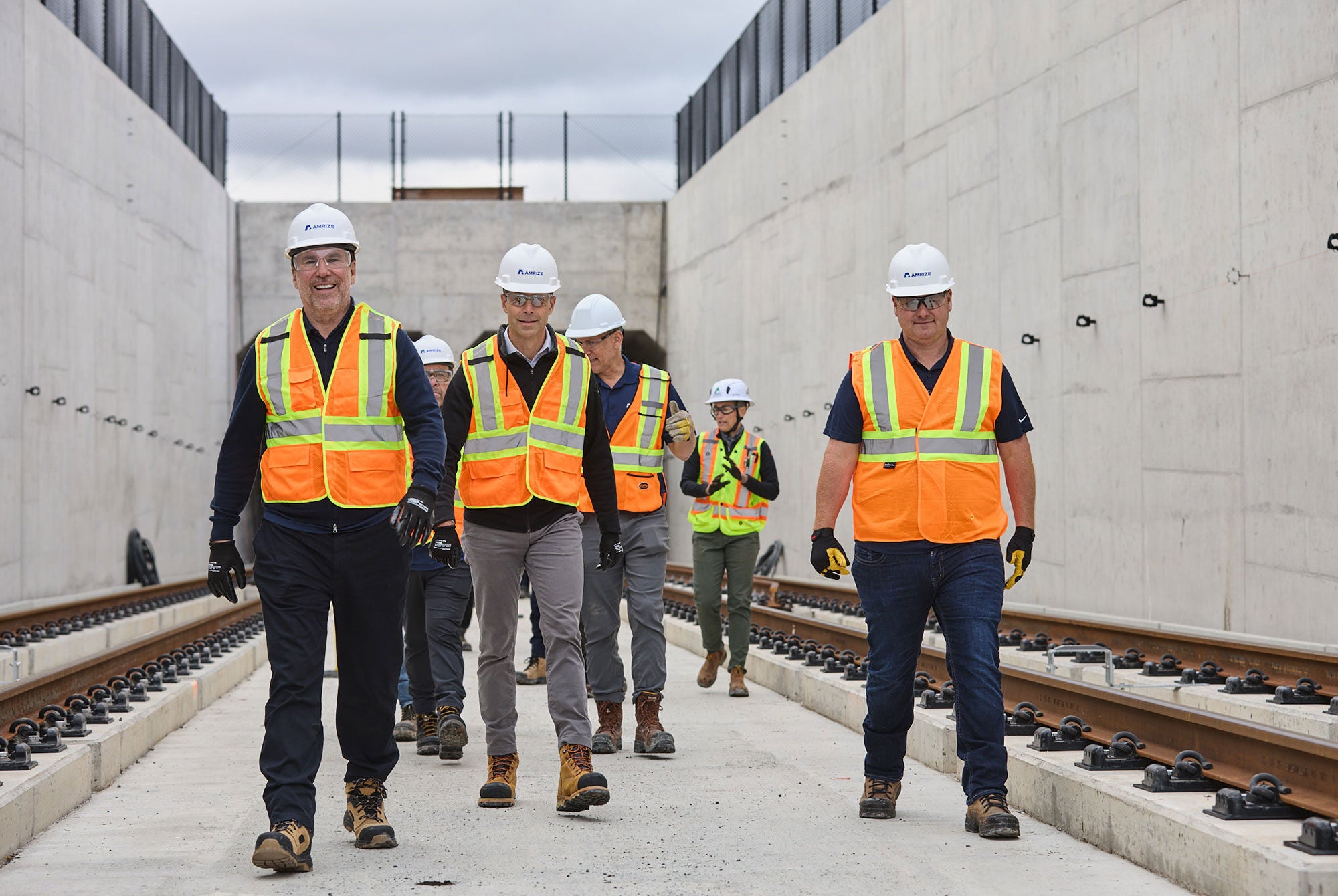 Leaders in hard hats and safety vests walking away from the entrance to a train tunnel
