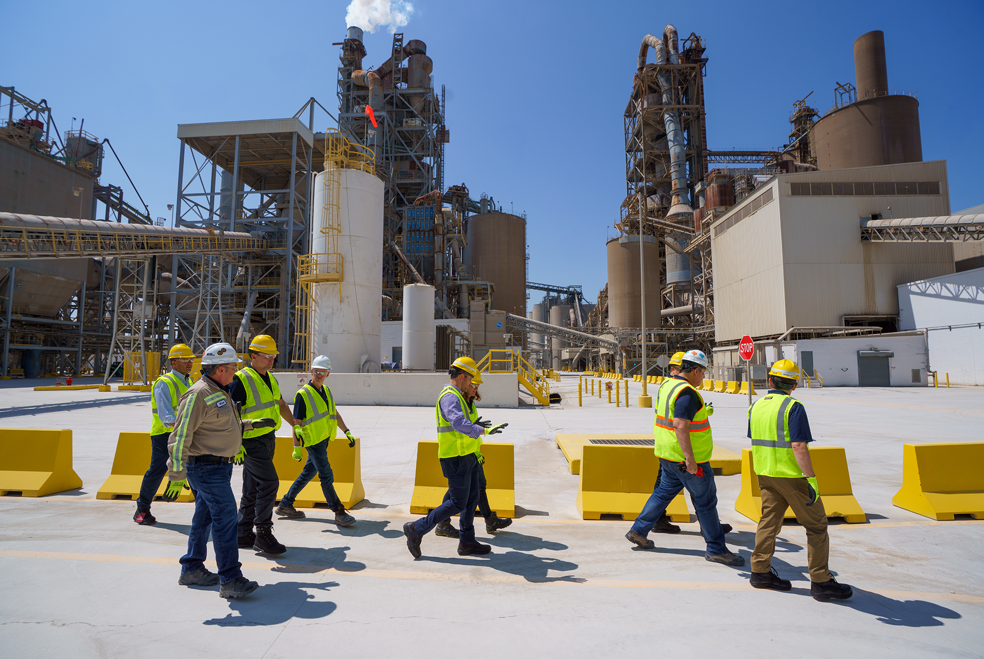 A group of workers in personal protective equipment walk through a cement plant