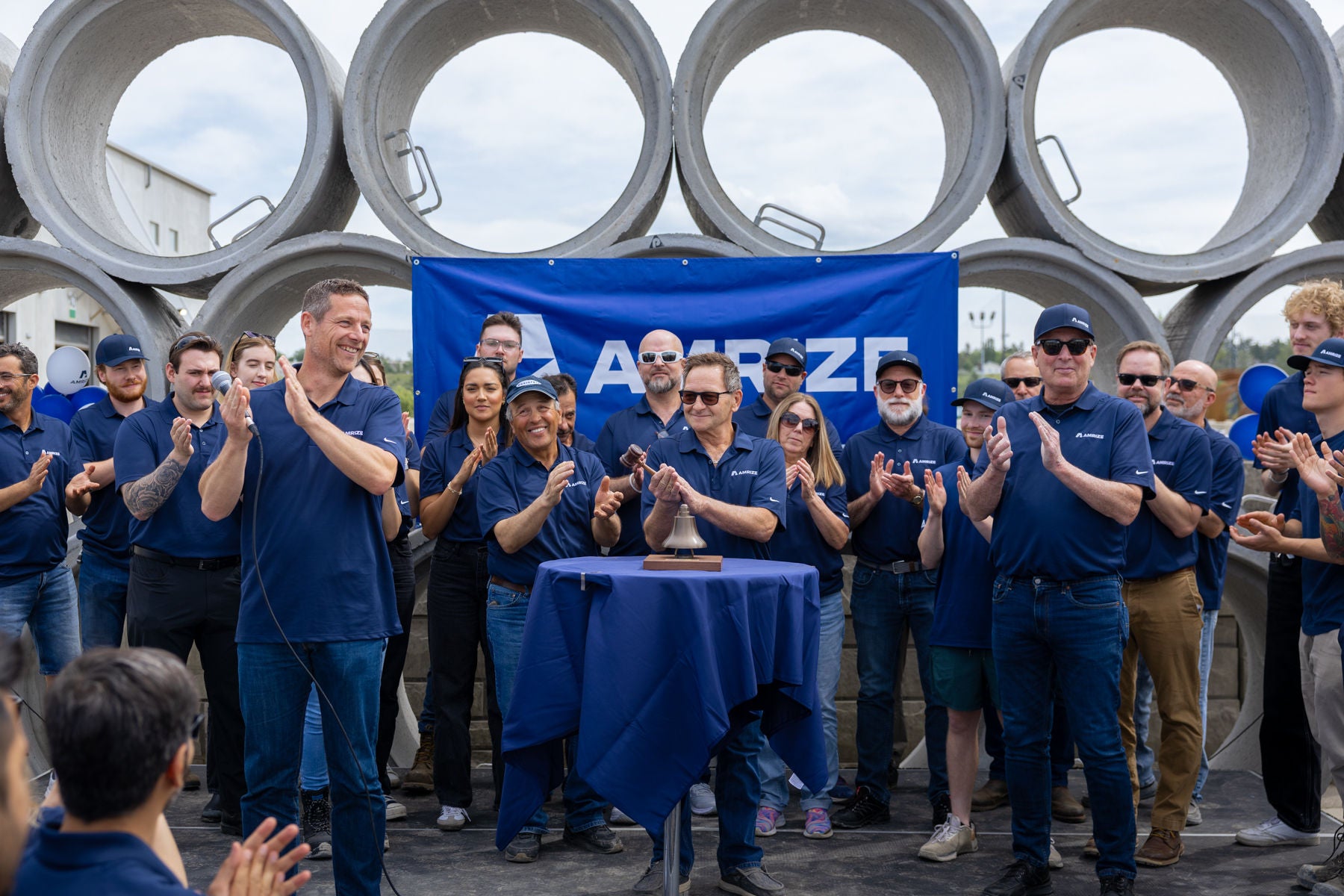 A group of employees gathered in front of concrete pipes