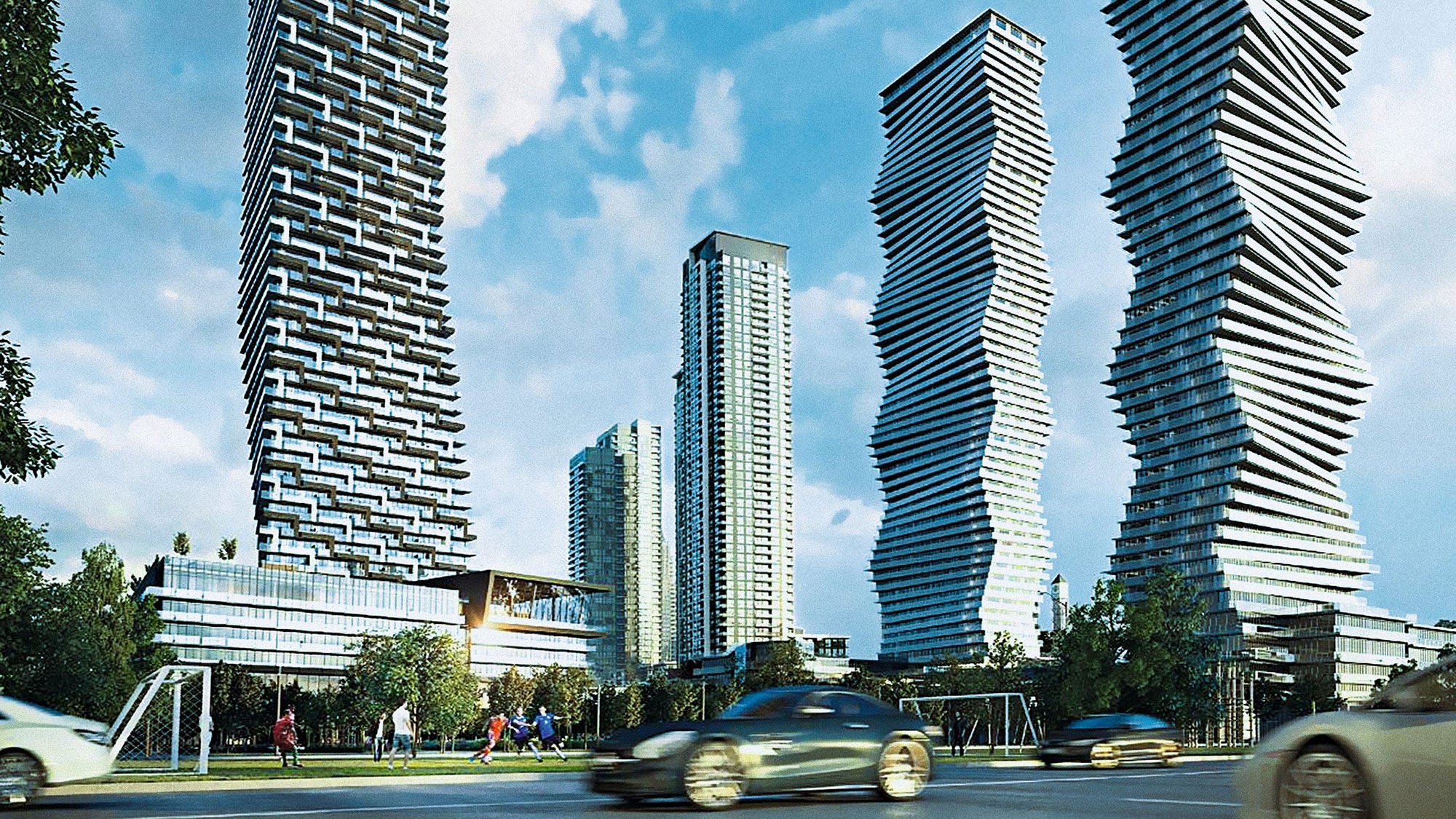 A car drives along a street lined with the M City tall buildings under a clear blue sky.