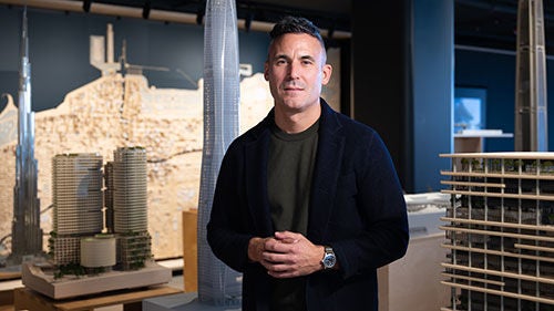 A man stands in front of multiple architectural models